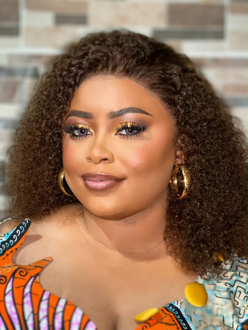 Maquillage de cérémonie doré, coiffure volumineuse bouclée et tenue en pagne