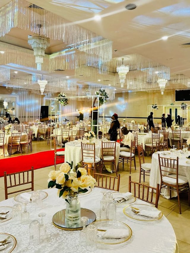 Salle de réception dressée pour une cérémonie, tables fleuries et lustres